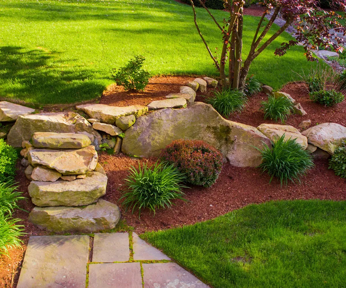 Landscaped front yard with boulder retaining wall and planting beds